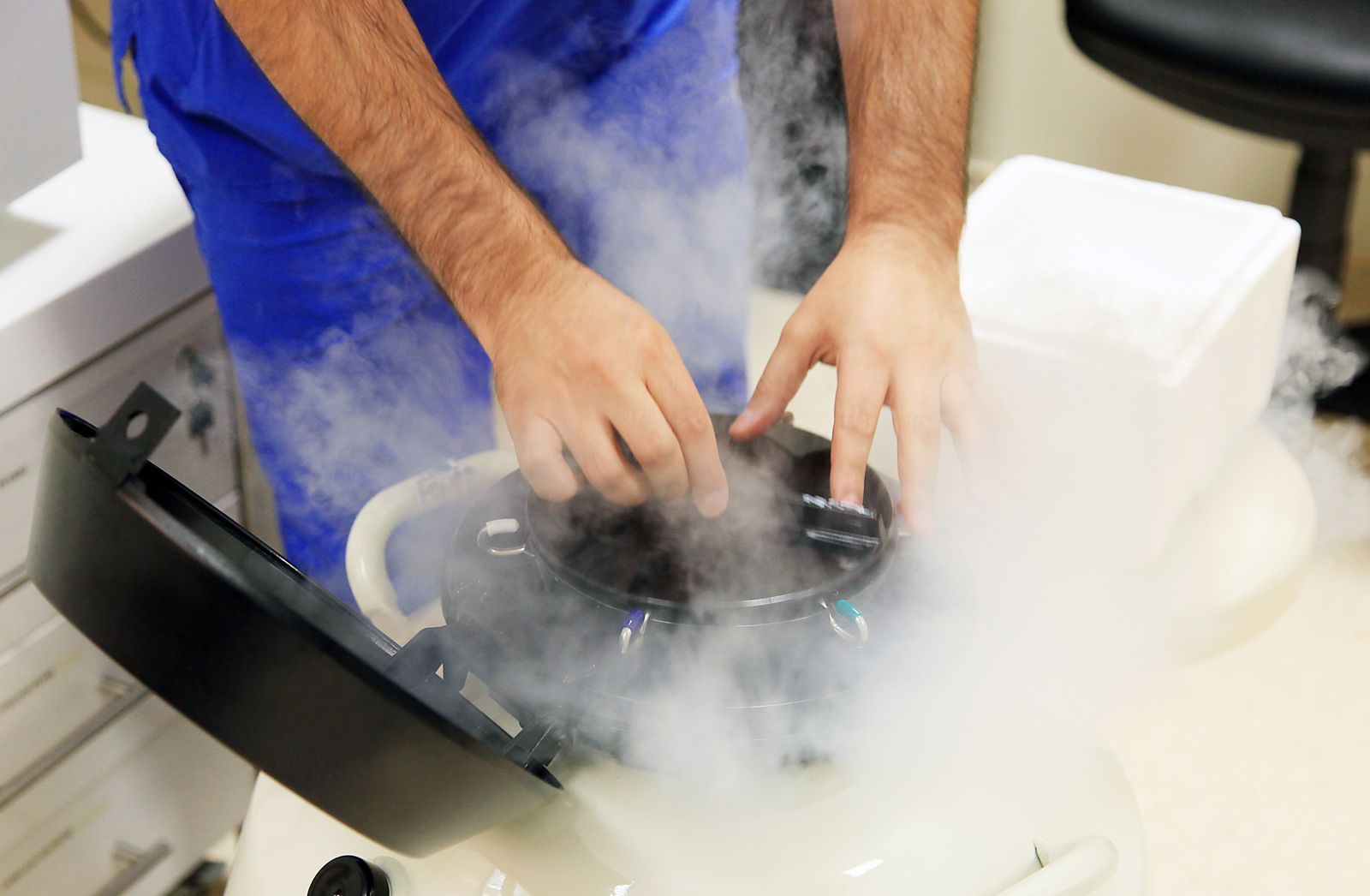 Specialist handling a cryogenic storage tank with liquid nitrogen, preserving biological samples for fertility treatments.